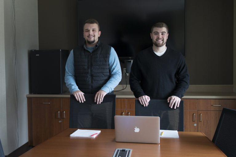 Two students standing around a desk